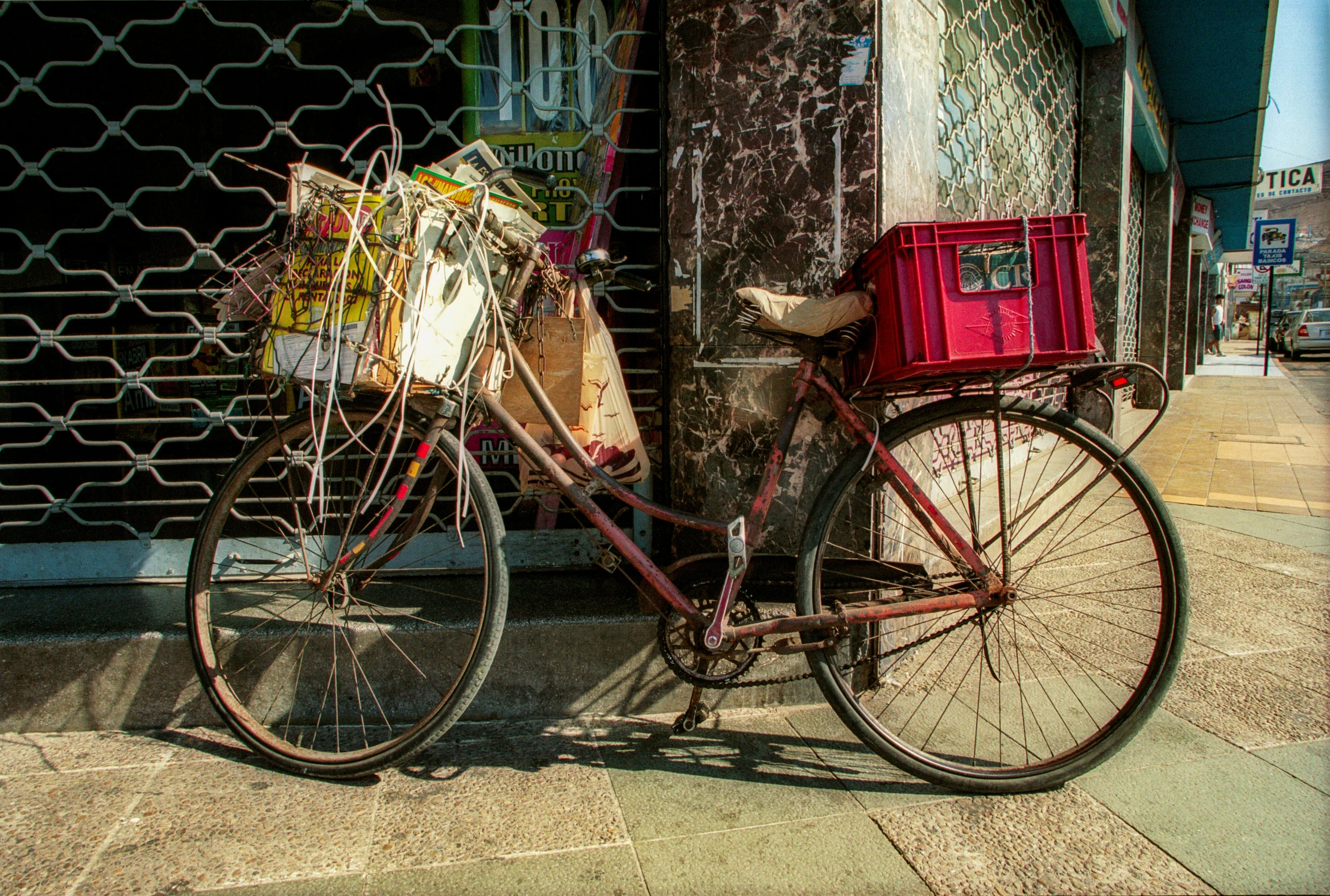 the bike has two crates in it and is parked next to the pole