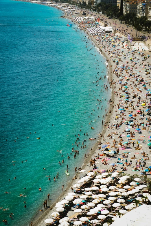 the beach is busy with many people with umbrellas