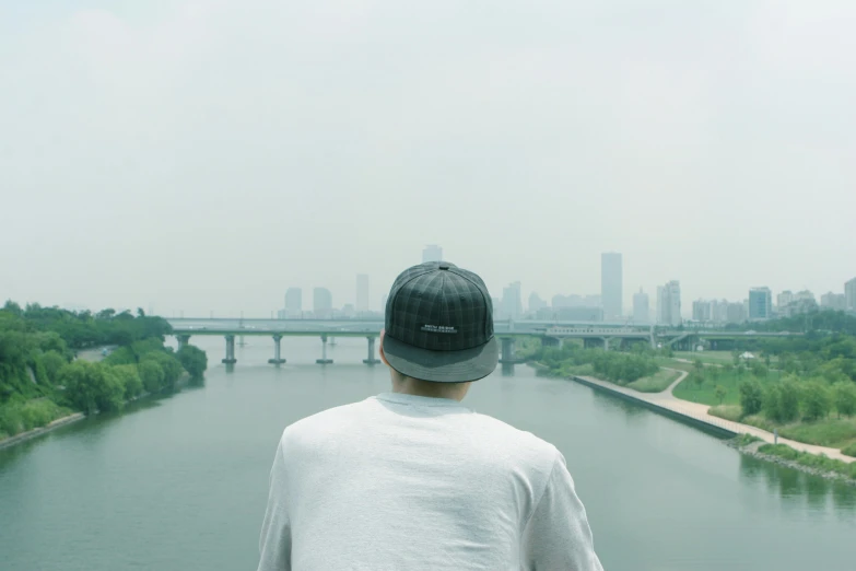 man standing near the side of the river looking at a city