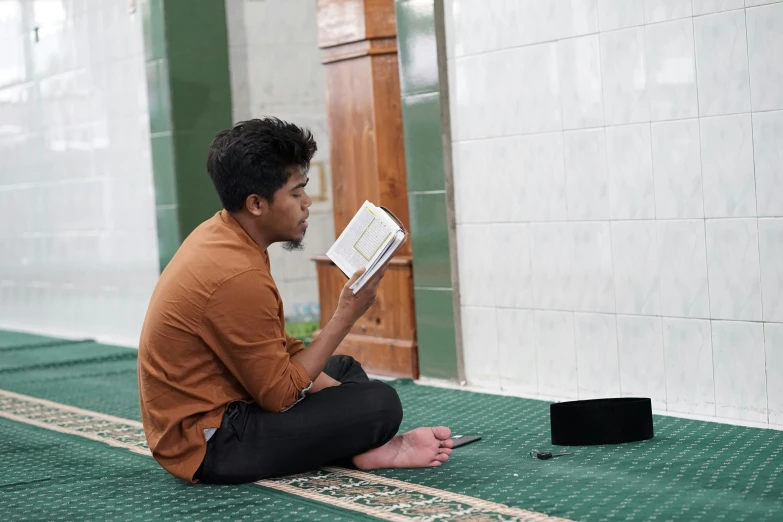 a man in brown shirt reading a book