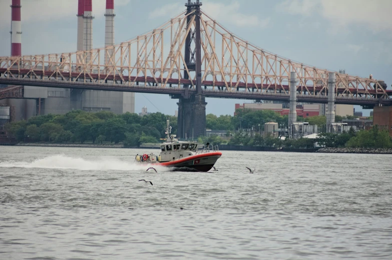 a boat sailing through the water in front of a bridge