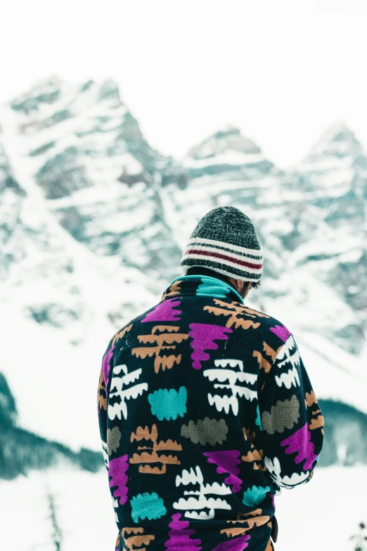 person wearing colorful sweater standing on snow covered mountain