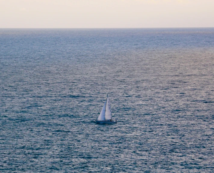 white sail boat with sail in large open blue water