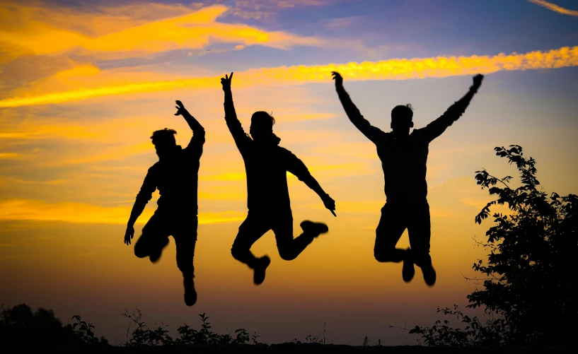 three young people standing in the sun with their arms up