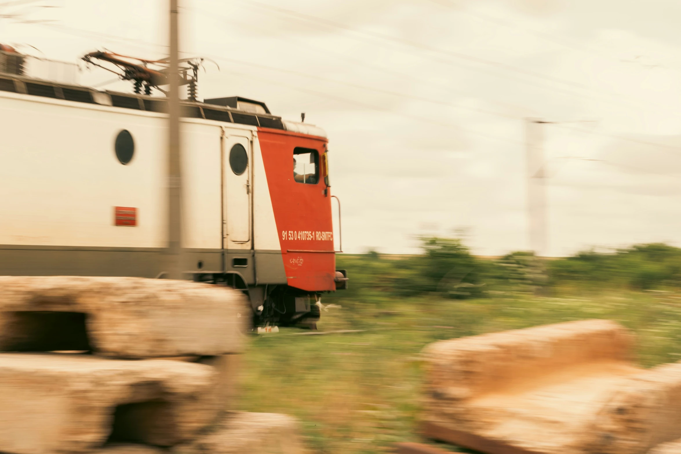 a red and white train traveling by a rock pile