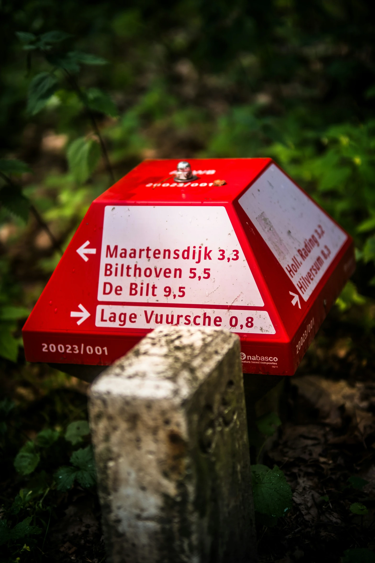 red sign in the woods pointing to different areas