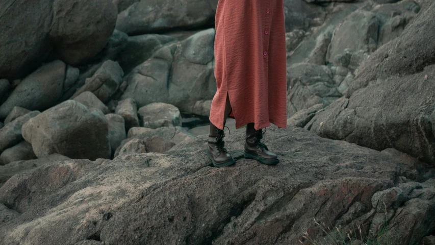 a woman standing on the rocks on top of rocks