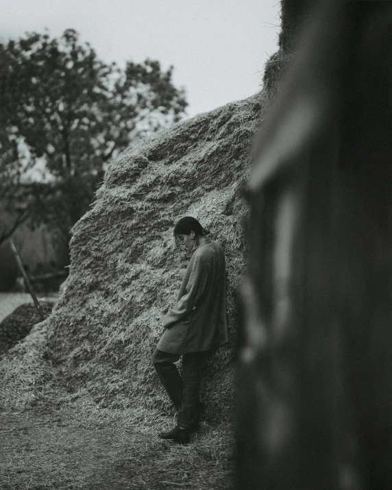 a person sits on a rock and looks out from behind the rocks