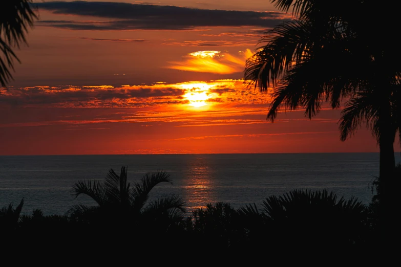 an orange sun and red clouds at the top of water