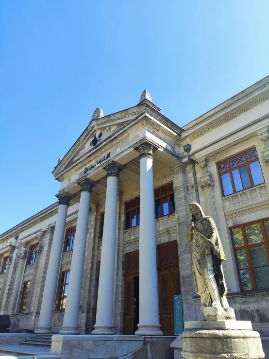 the building has some very tall columns and statues outside