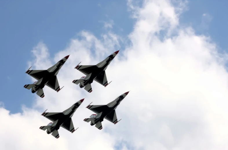 four jets flying in the sky with fluffy clouds