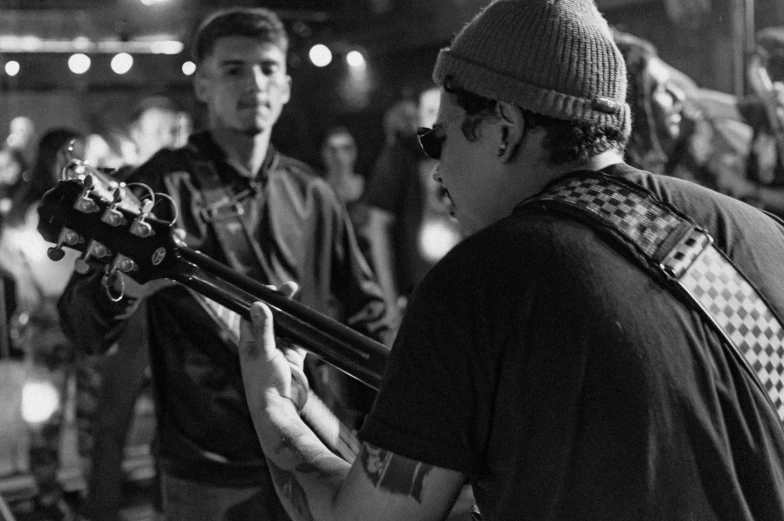 a man standing next to another man holding a guitar