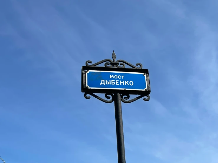 a sign for most alamge hxo is attached to a black pole with a blue sky in the background