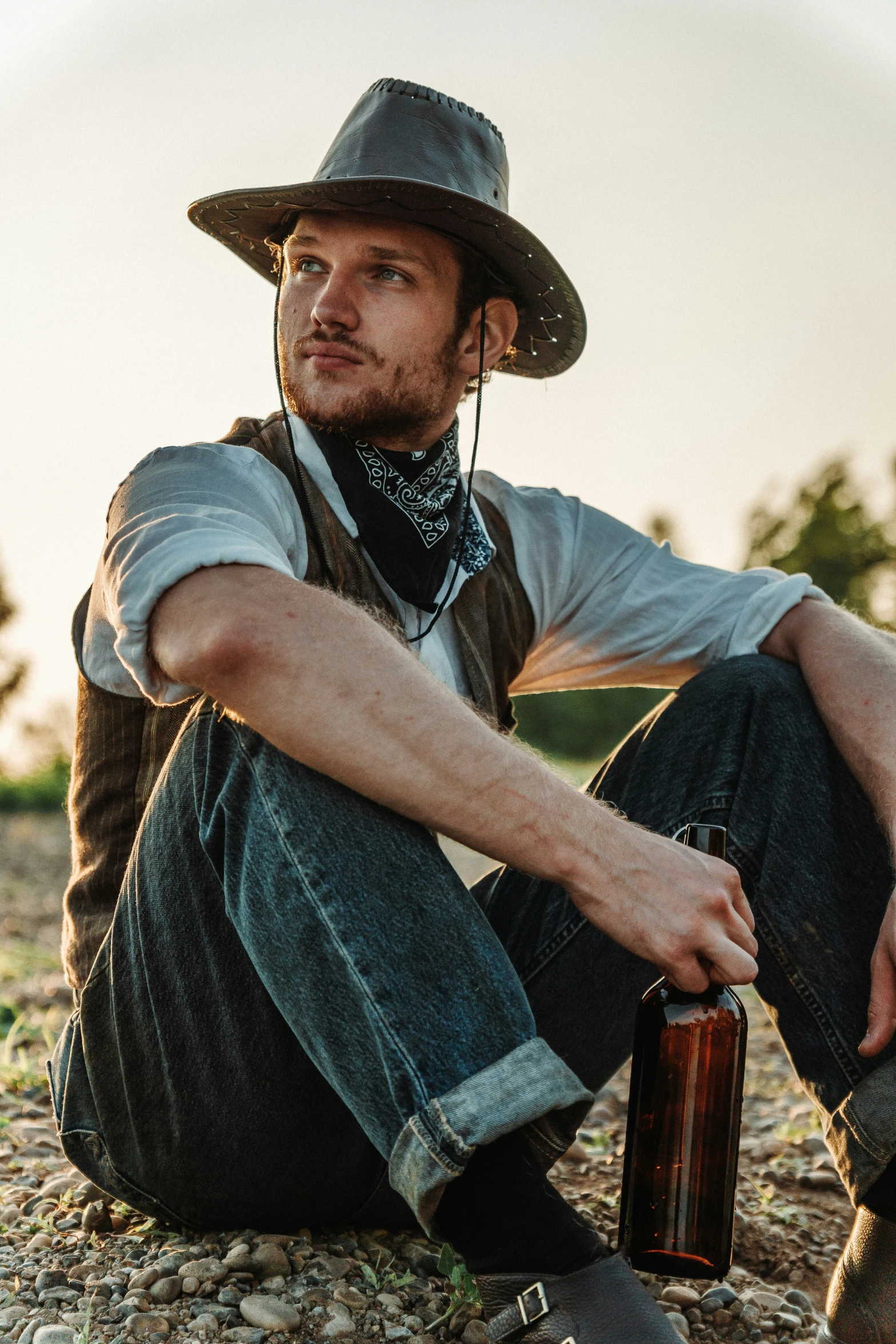 a person sitting on the ground next to a beer