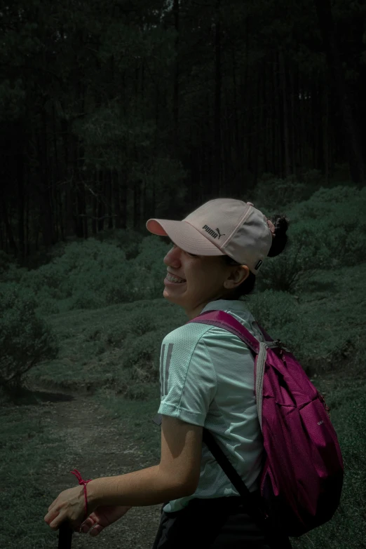 woman hiker in a cap and backpack looks to the side on a dark, foggy day