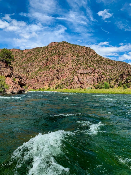 the waves of a boat on a lake with a mountain in the background