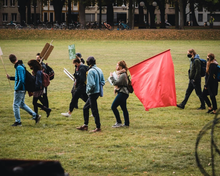 several young people carrying signs walking in the grass