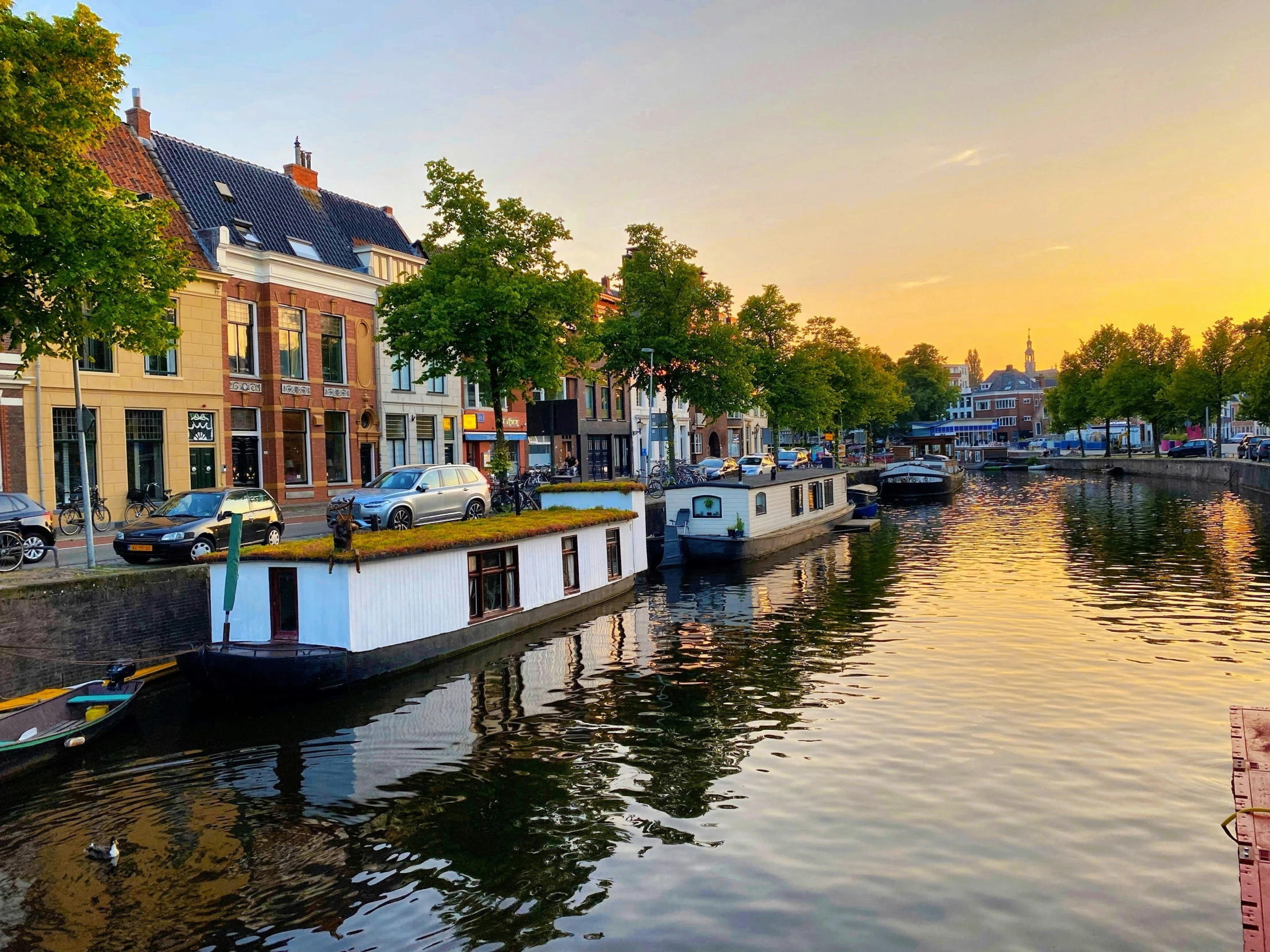 two boats at dock with city buildings and sun setting