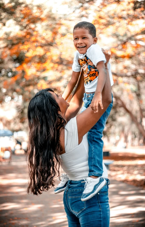 a woman is lifting a small child on her shoulders