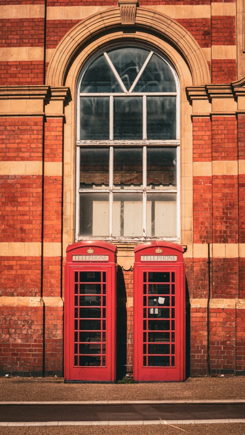 a couple of large red phone booths in front of a window