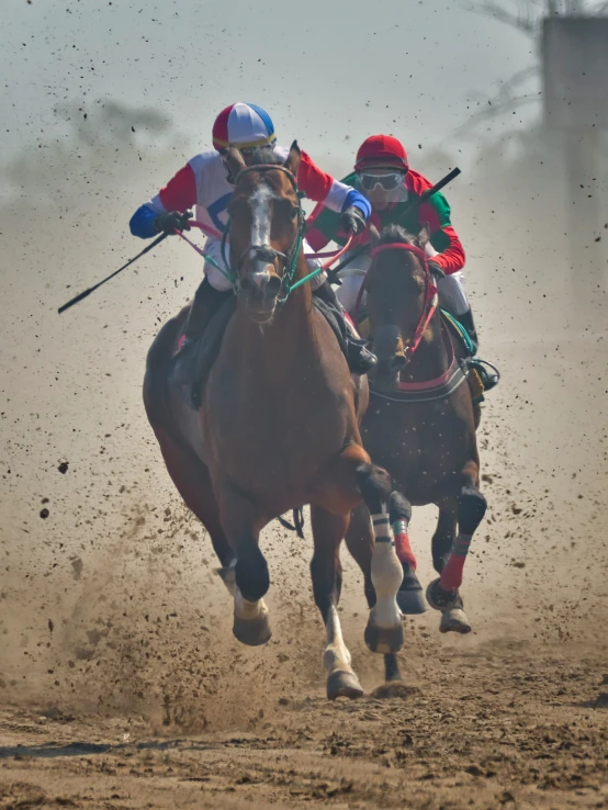 two jockeys on horses galloping in the dirt