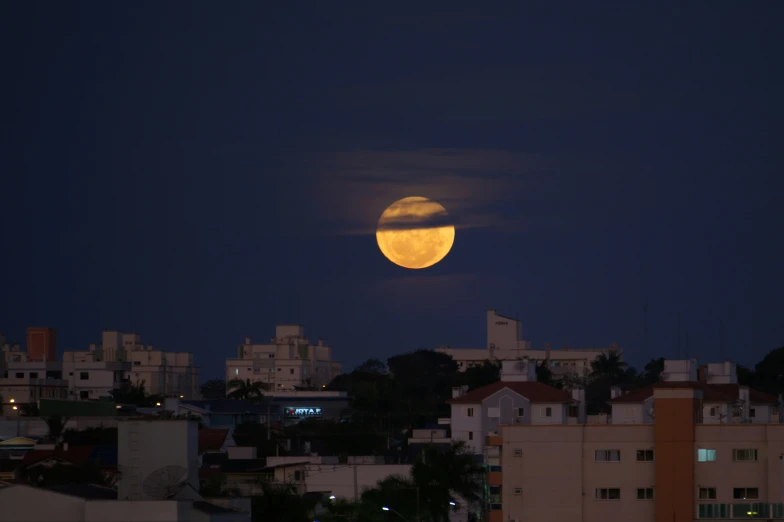 the full moon rises above the city skyline