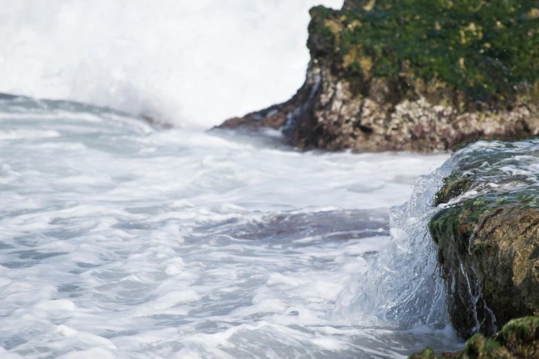 the wave crashes on the rocks that are just starting to break