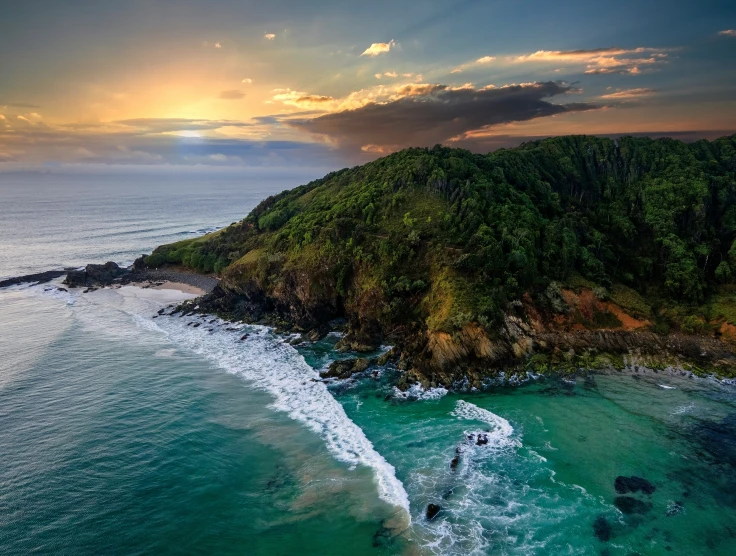 an aerial view of a beach and ocean at sunset