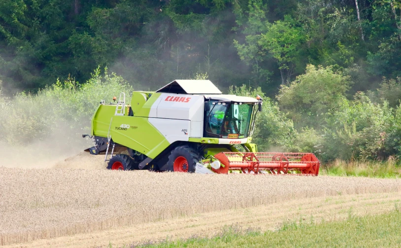 a large green tractor with a red hitch driving through a field