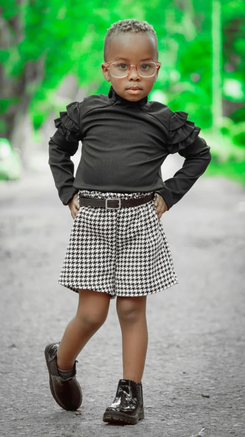 a small girl in a skirt with her hands on her hips