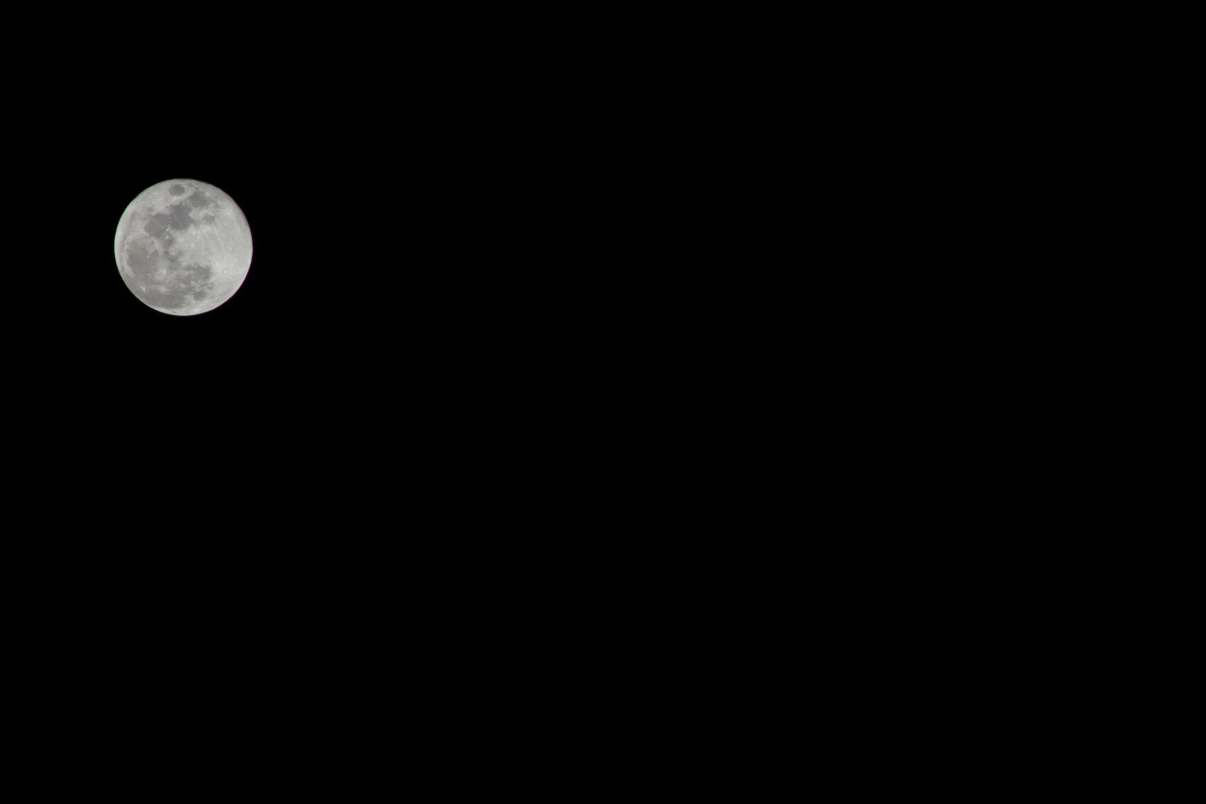 a plane flying past the moon in the dark sky