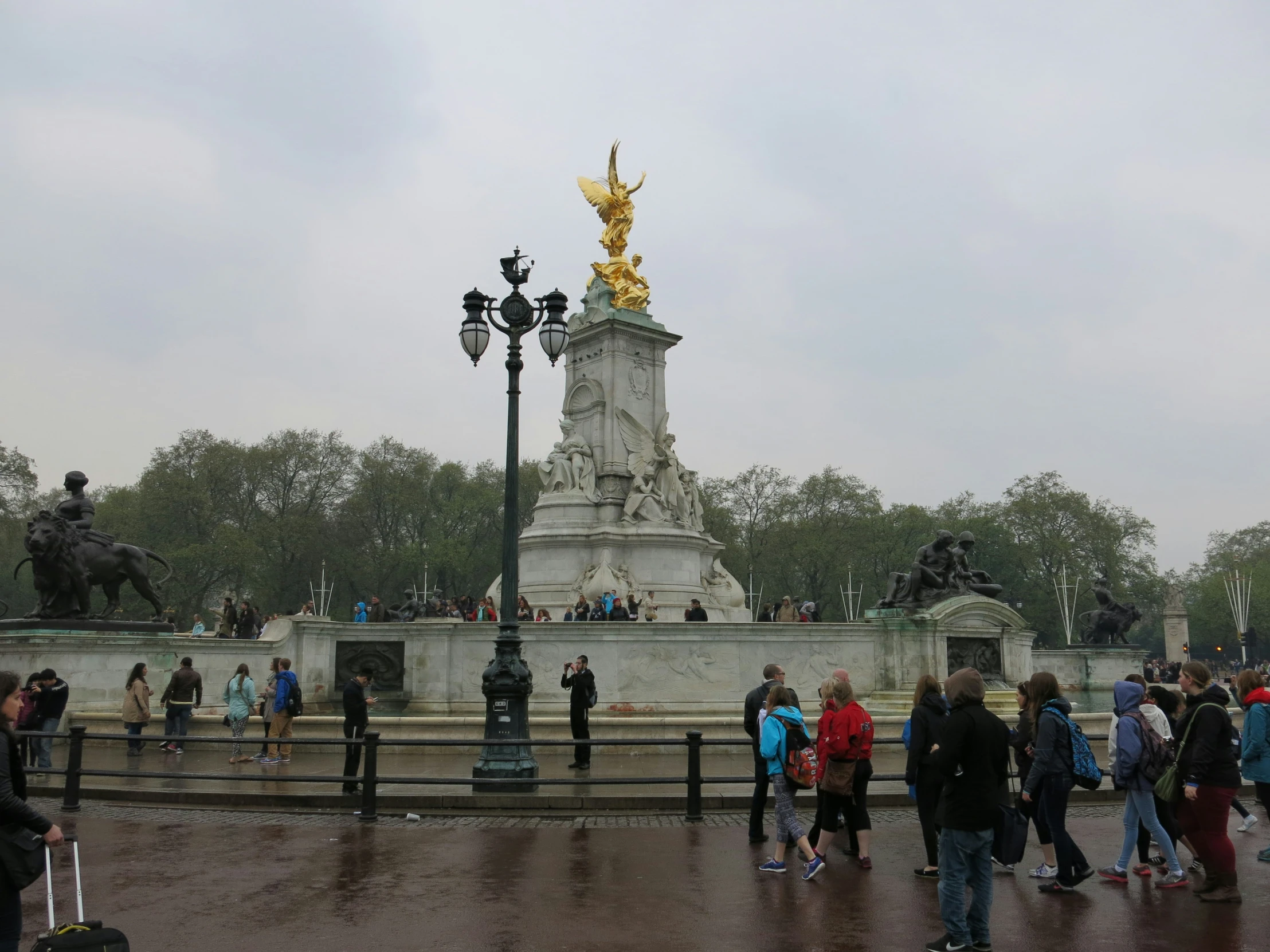 many people walking in front of a statue in a park