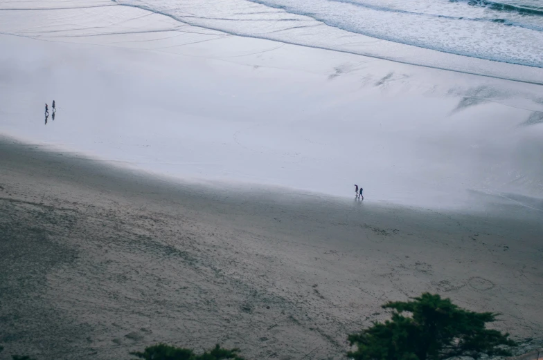 two people walking on the beach toward the ocean