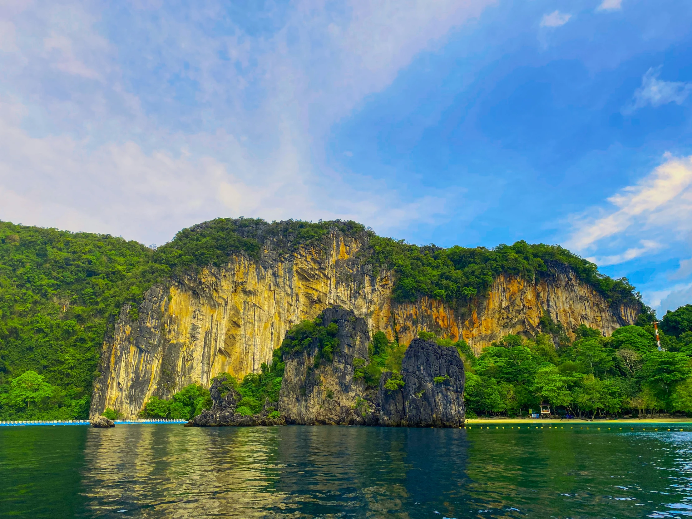 a blue boat on the water with a cliff in the background