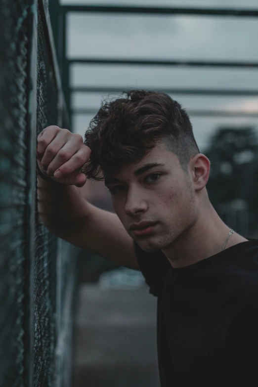 a man with wavy hair looking away against a wall