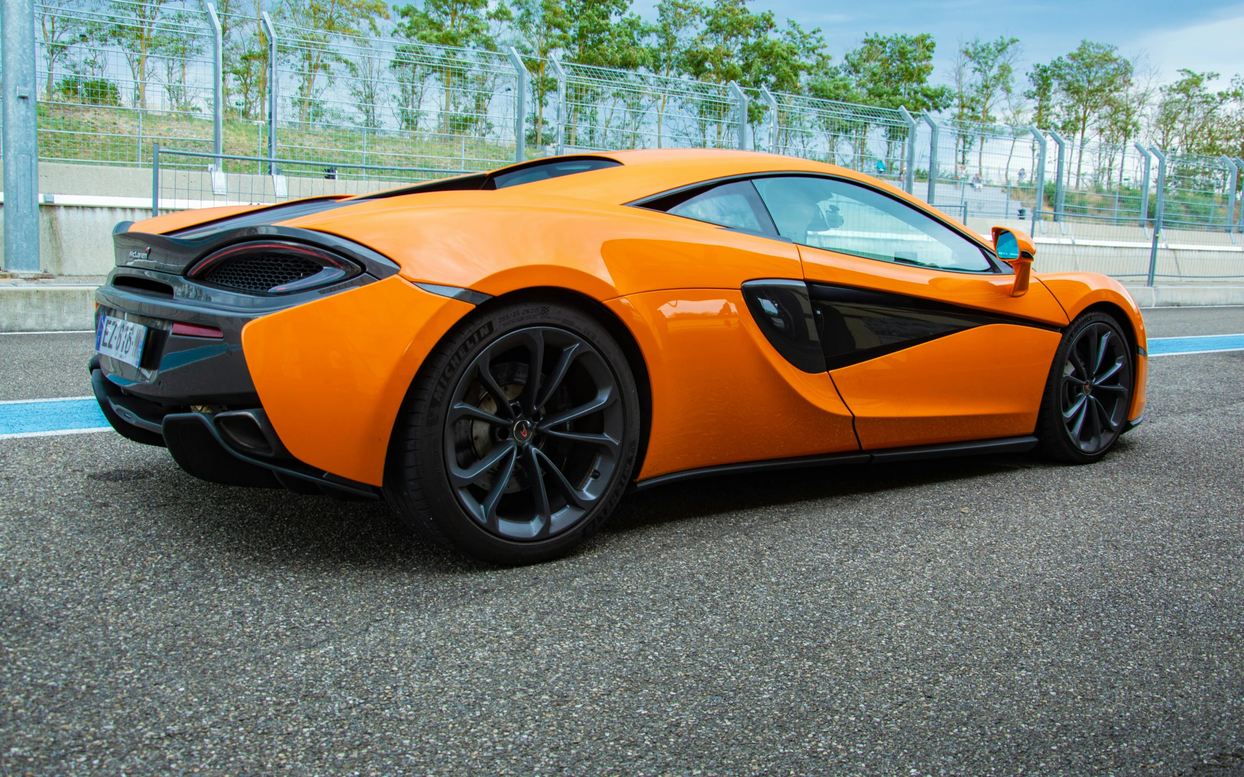 an orange sports car is parked on the side of the street