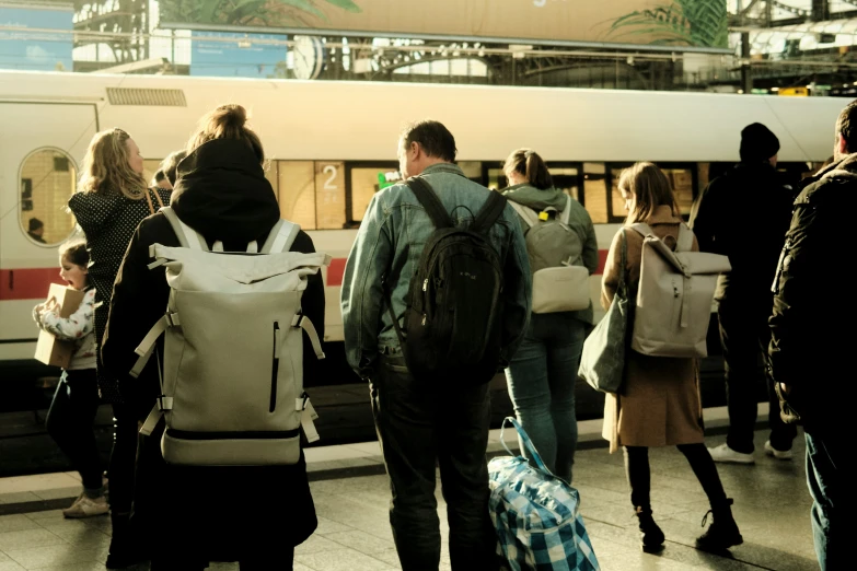 a group of people carrying luggage towards a train