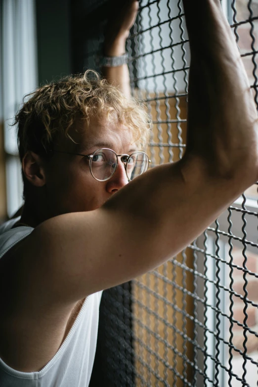 man leaning on chain link fence next to large window