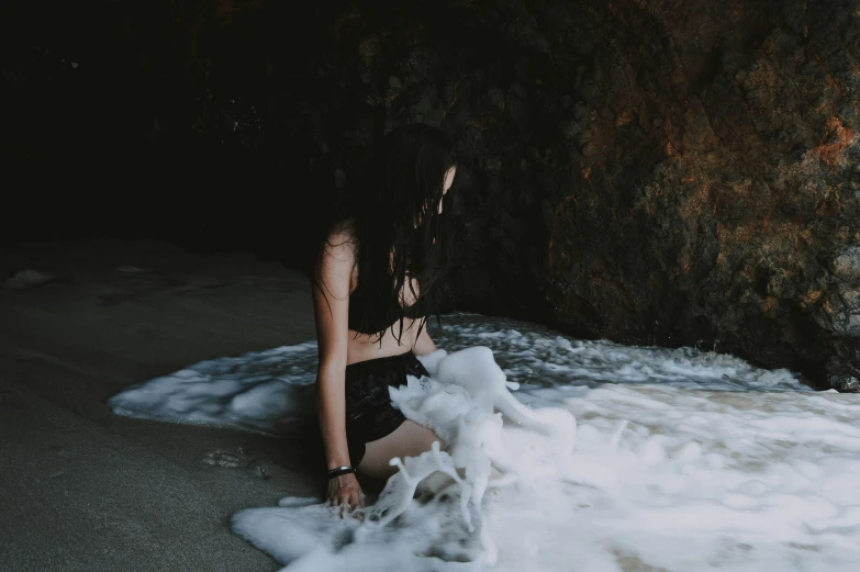 a woman in black swimsuit in water next to rock