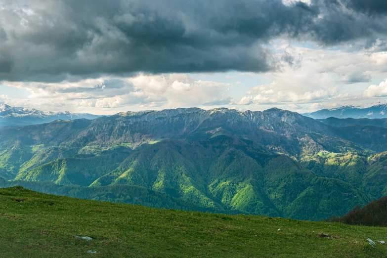 the clouds and mountains are covered in light green vegetation