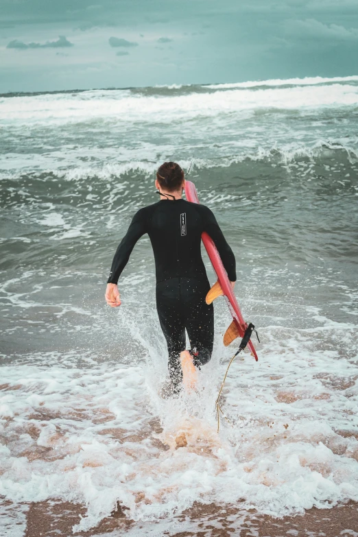 the man is walking in the waves with his surfboard