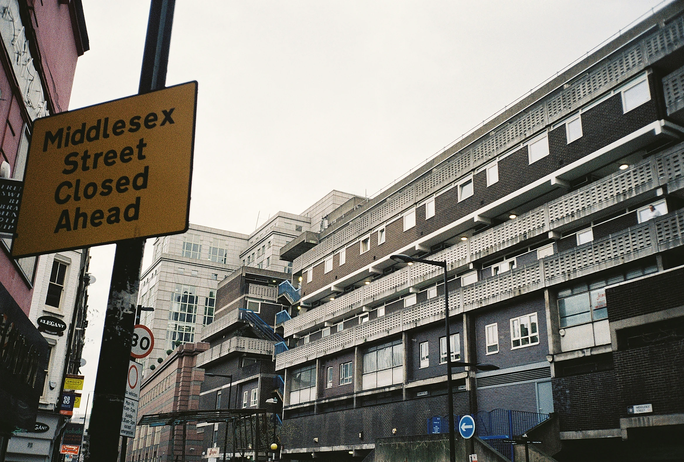 a street with buildings is near a fence and cars