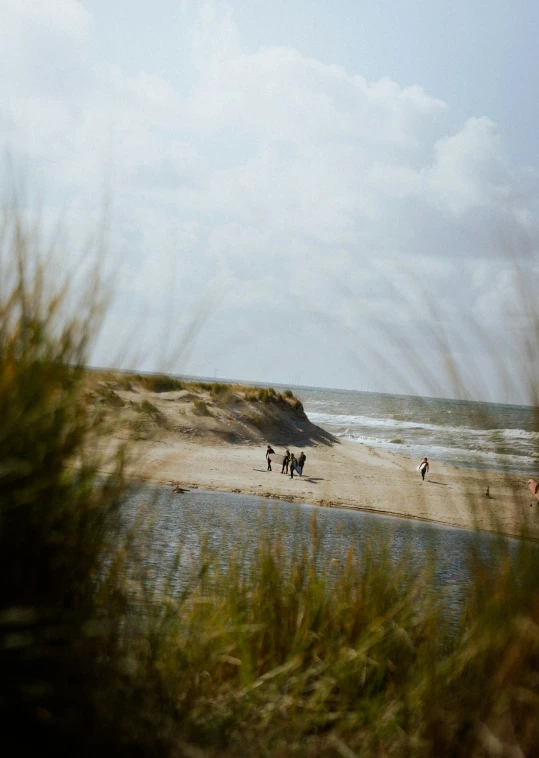 three people are walking on a sandy beach