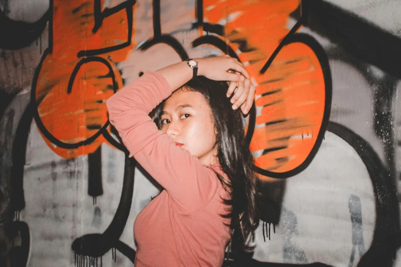 a girl is posing in front of graffiti