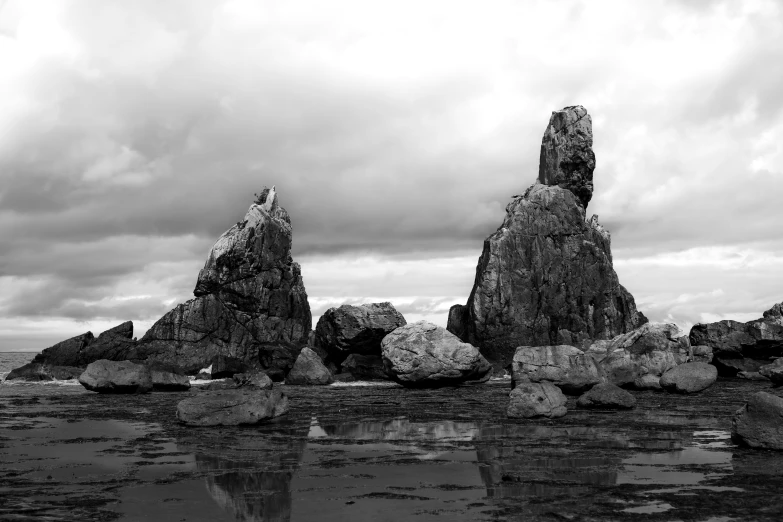 a group of rocks on the beach with sky in the background