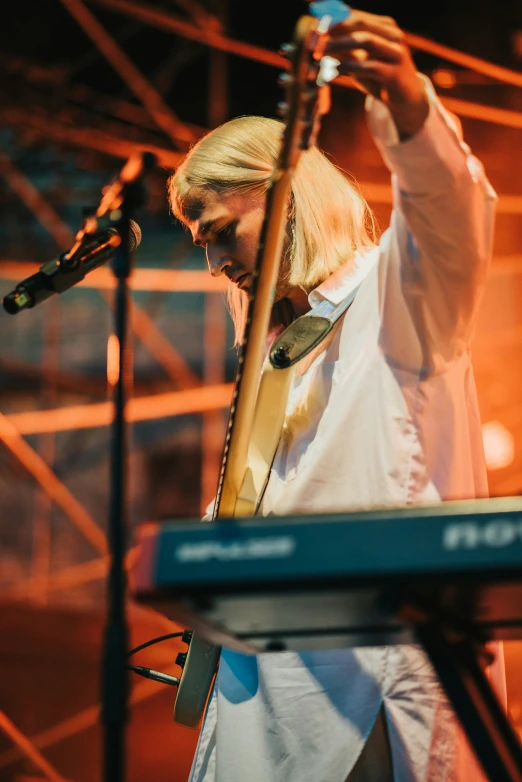 a person standing with a guitar in front of a microphone