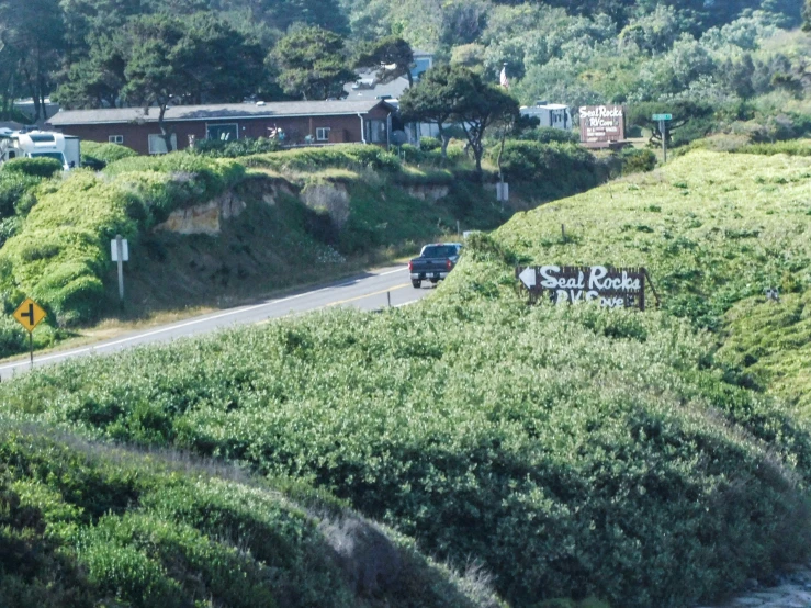 several cars drive by a street sign on the side of a hillside