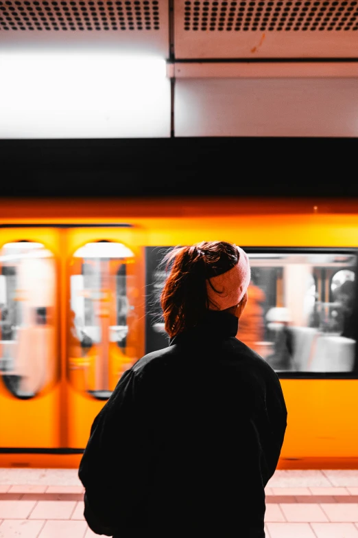 a woman is standing outside waiting for the subway