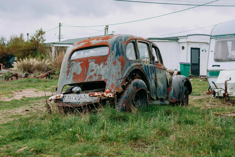 an old rusted down car is on the grass