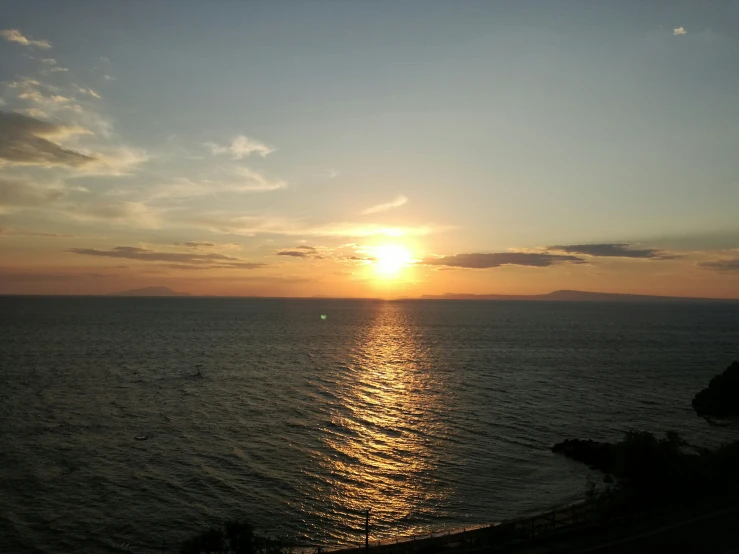 the sun sets over water at the ocean